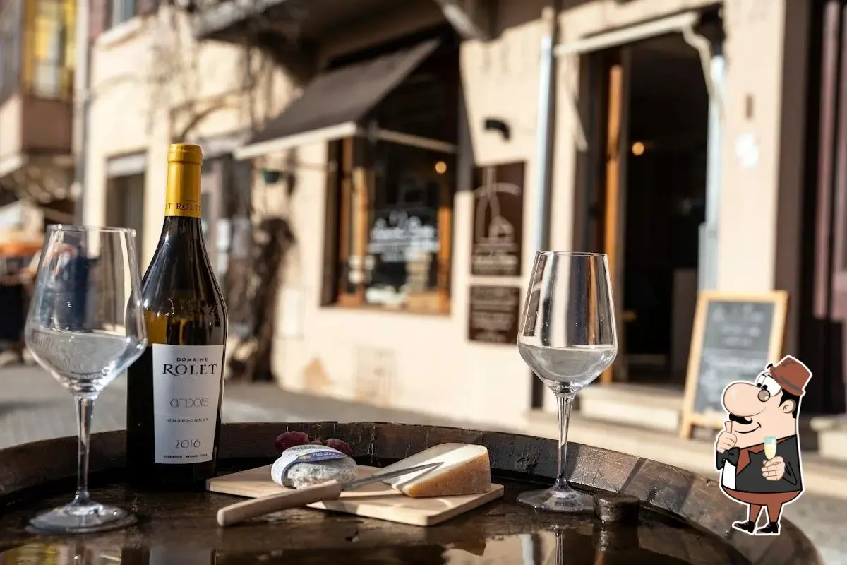 Bottle of white wine, glasses and cheese board on a barrel in front of Les 2 Caves wine shop