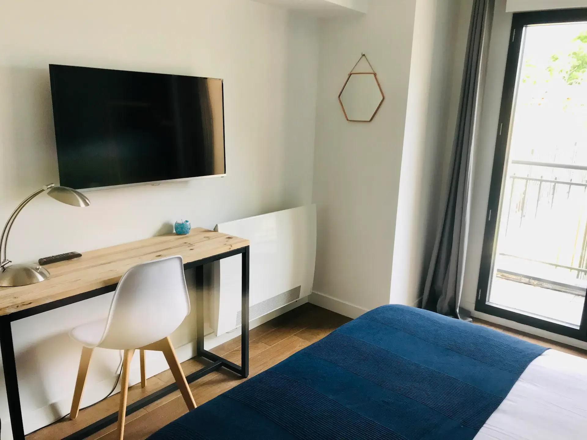 Desk corner of the Hermosa room: wood and metal desk, white chair, wall-mounted TV and terrace access