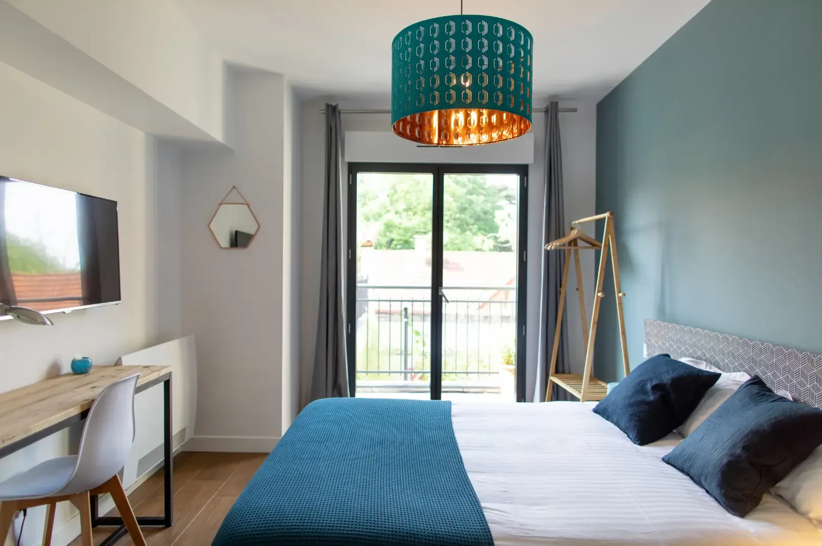 Hermosa room: double bed, desk, turquoise pendant lamp and patio door onto the terrace