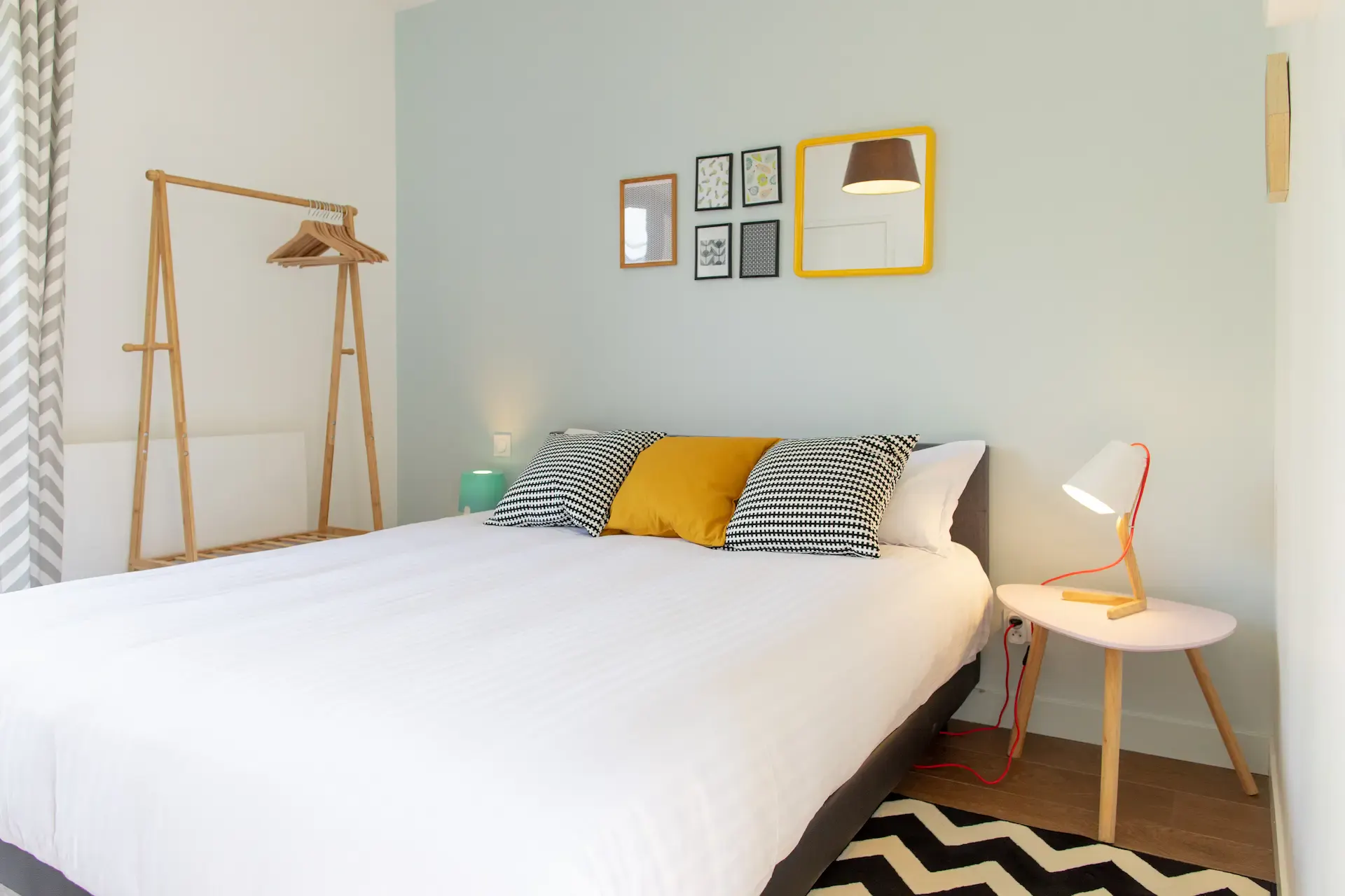Chambre Palermo : lit aux coussins rayés et jaune, portant en bambou et cadres au mur