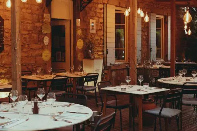 Dining room of the Restaurant de la Gare: stone walls, laid tables and pendant lights