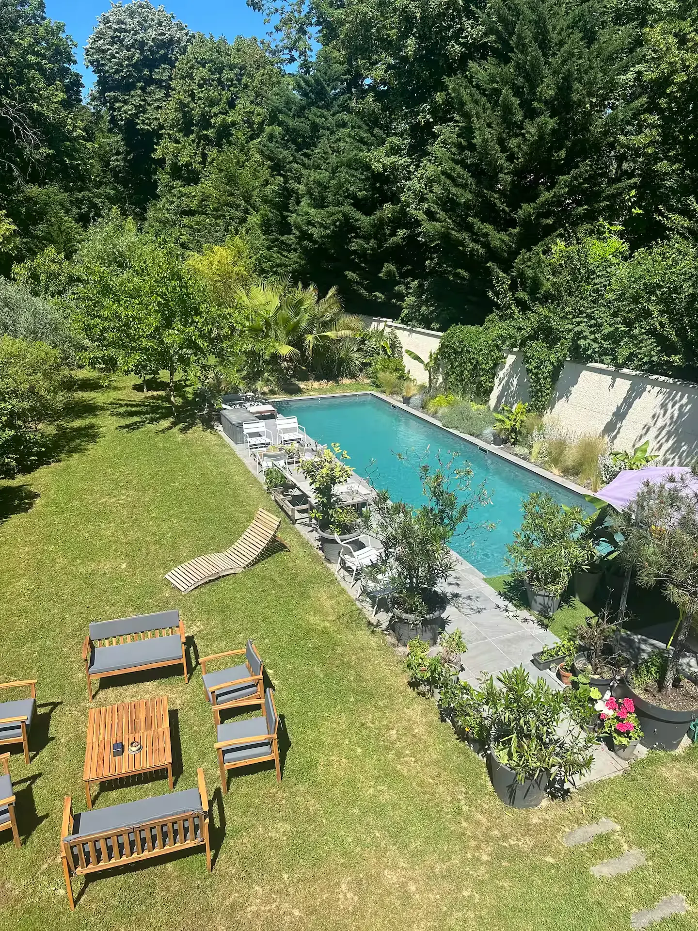 Jardin ensoleillé avec la piscine, les transats et le salon de jardin en bois