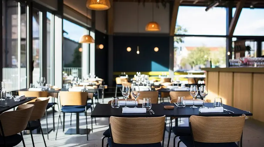 Glass-walled dining room of L'Éclat de Pierre, laid tables and view over the town