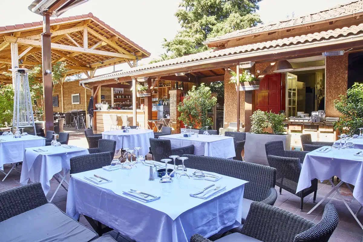 Shaded terrace of Le Comptoir de Saint-Cyr, tables laid with white tablecloths