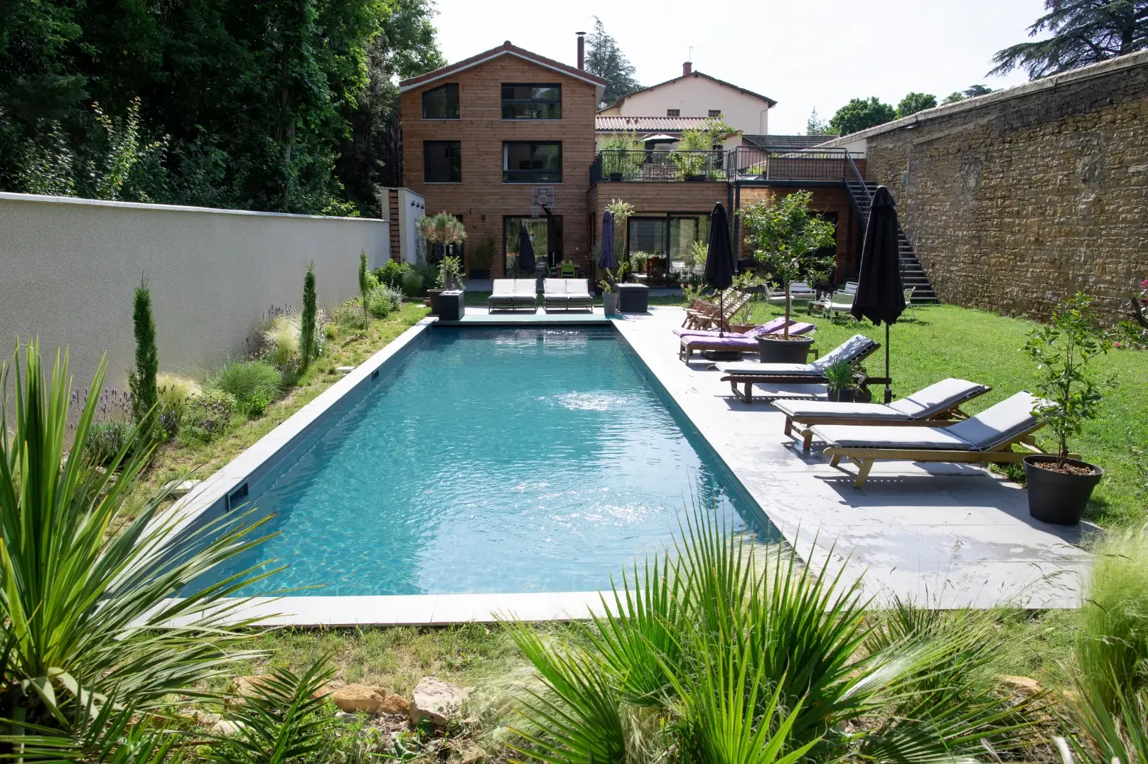 Piscine d'Effet Lodge, ses transats et la maison au fond du jardin