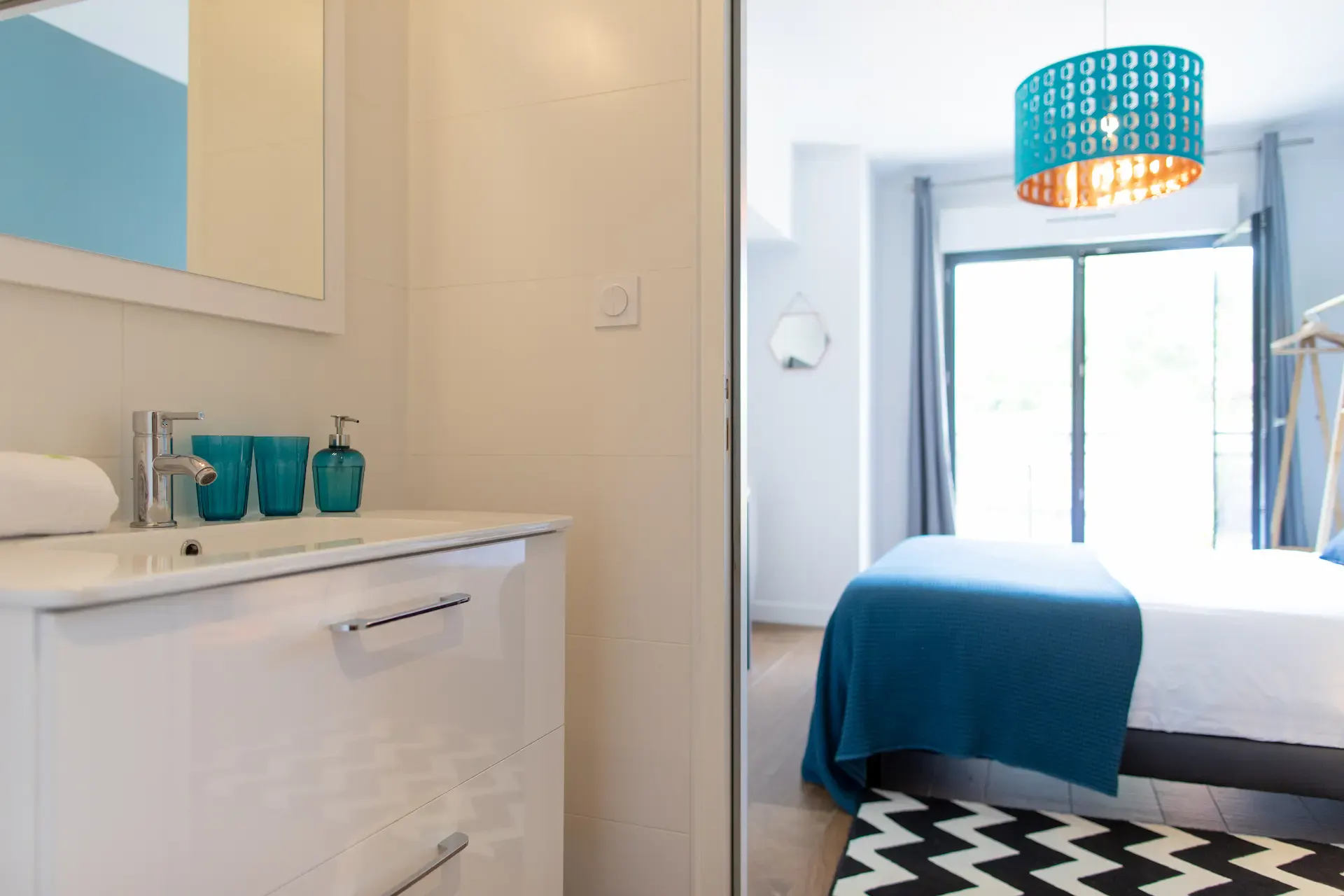 Hermosa room bathroom open onto the bedroom, white washbasin and turquoise accessories