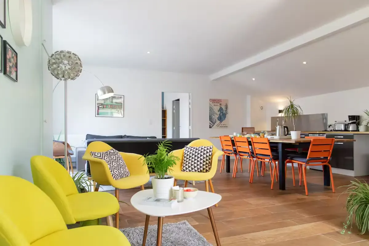 Salon commun aux fauteuils jaunes et salle du petit-déjeuner aux chaises orange
