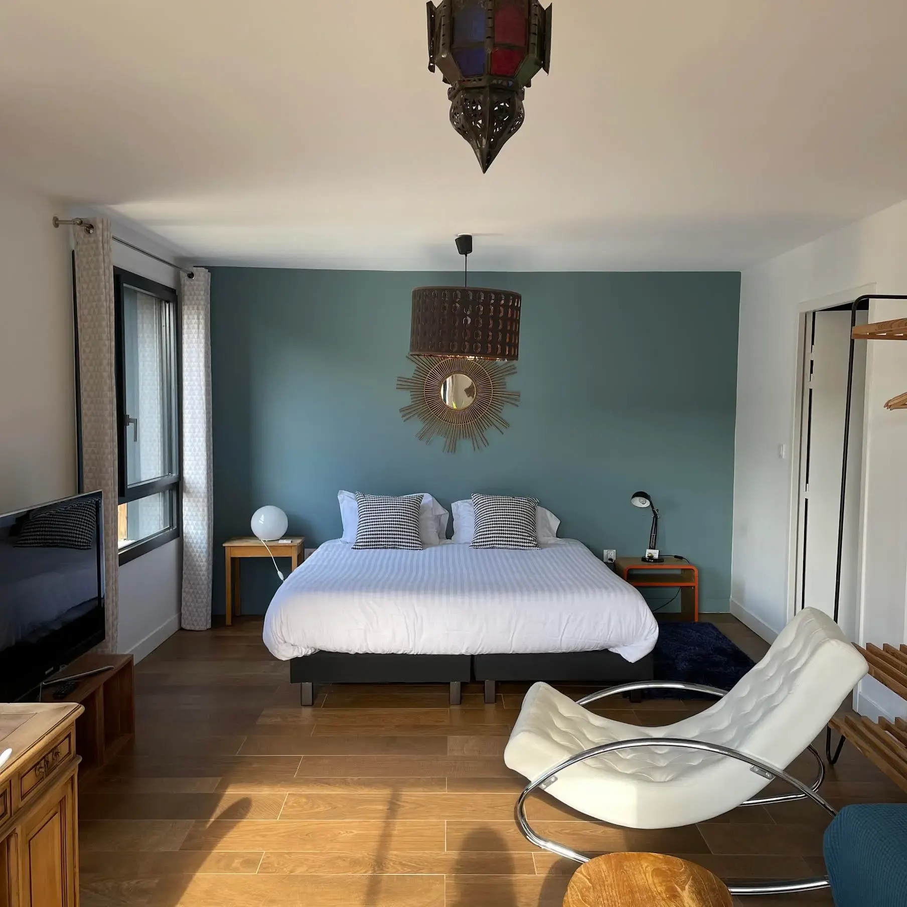 Suite familiale Jaïpur : grand lit, fauteuil blanc, suspension orientale et mur bleu