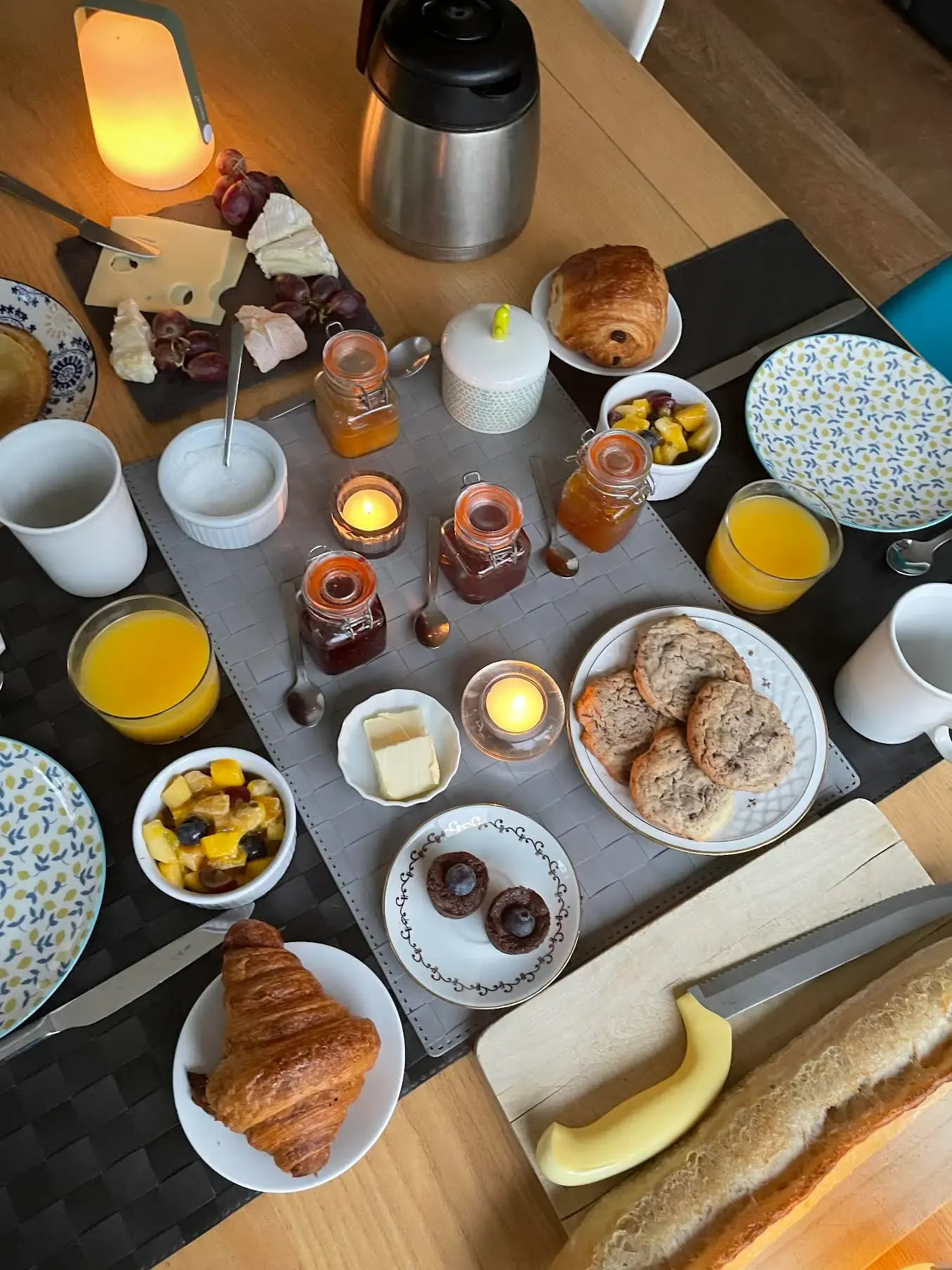 Petit-déjeuner servi sur la table : viennoiseries, pain, confitures maison, salade de fruits et jus d'orange